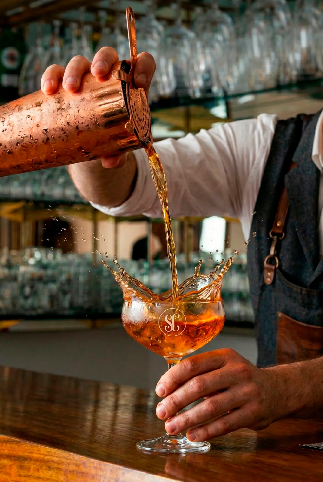 Cocktail poured from a copper shaker into a glass with the Sa Costa monogram