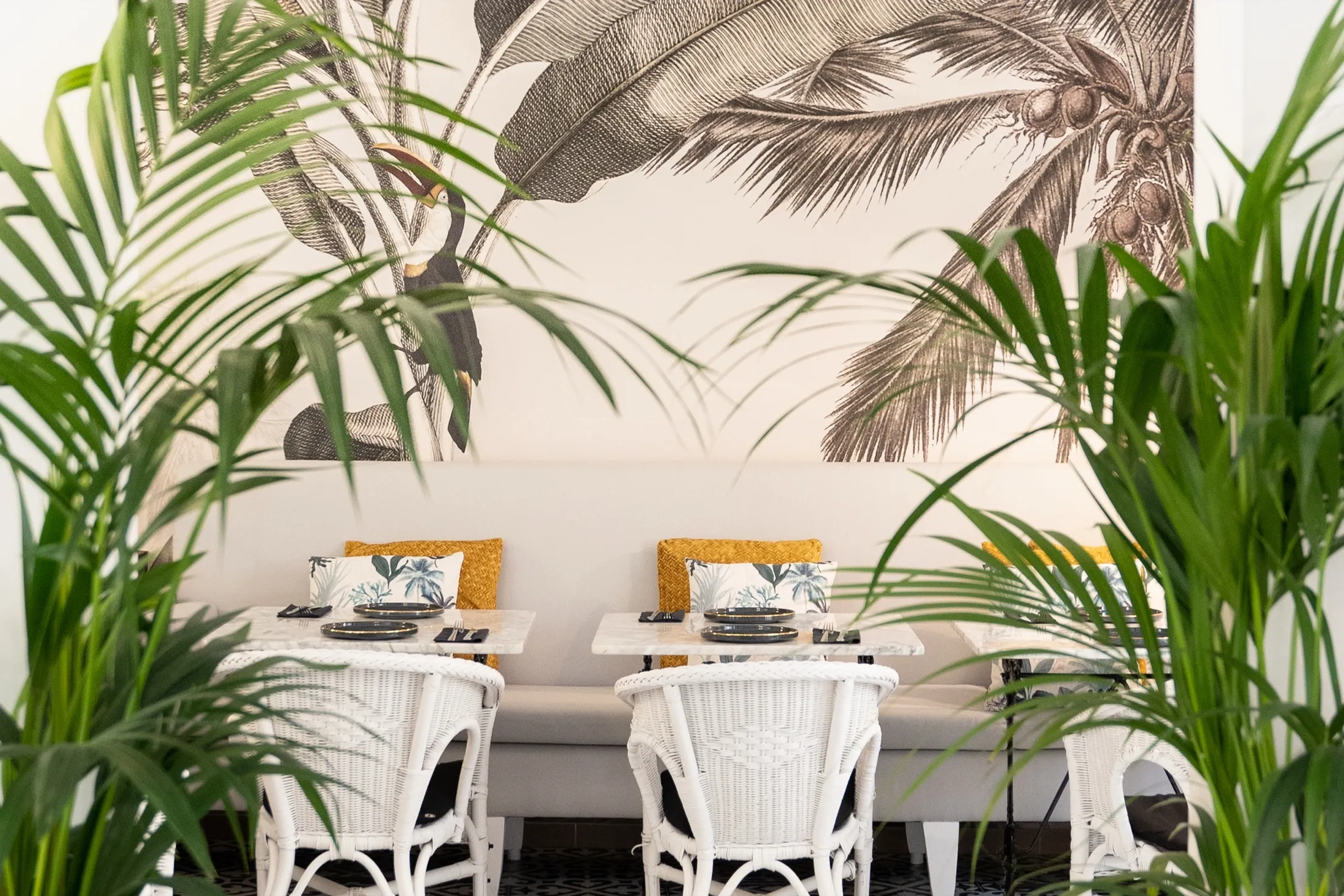 Comedor de Sa Costa con papel pintado de palmeras y sillas de mimbre