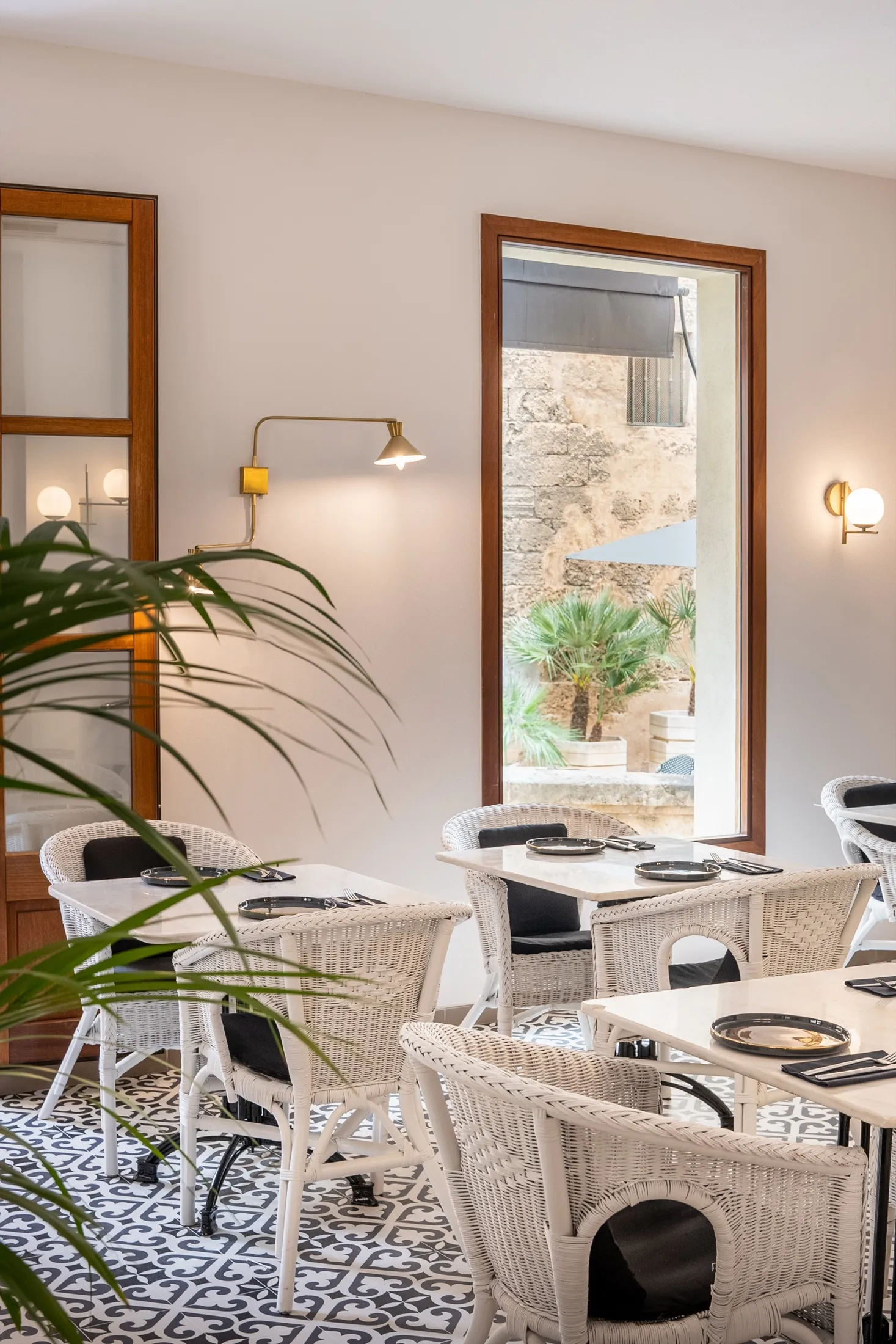 Comedor de Sa Costa con sillas de mimbre, plantas y ventana a la calle